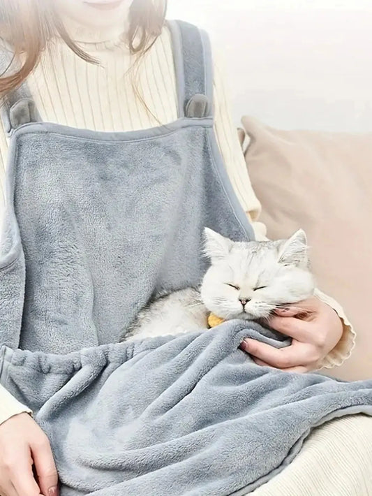 Person holding a cat wrapped in a gray blanket with a neutral background